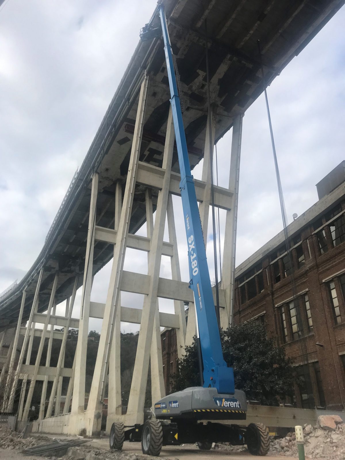 Two Genie SX-180 boom lifts involved in a high-precision demolition process in Italy